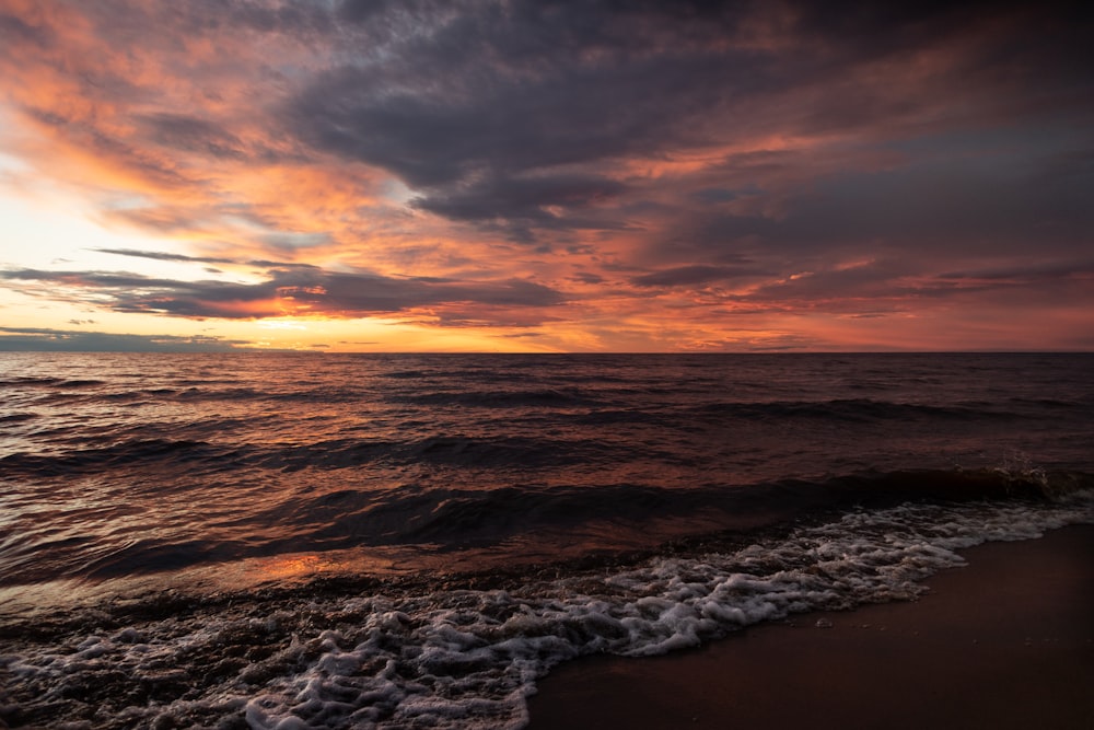 ocean waves crashing on shore during sunset