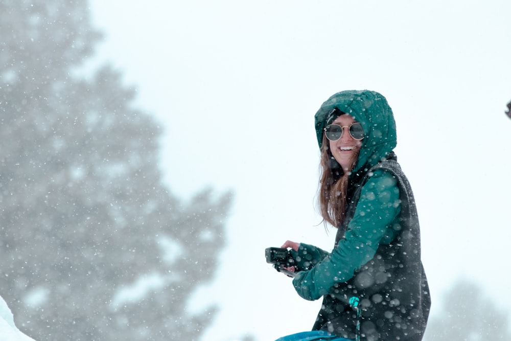 a woman standing in the snow holding a cell phone