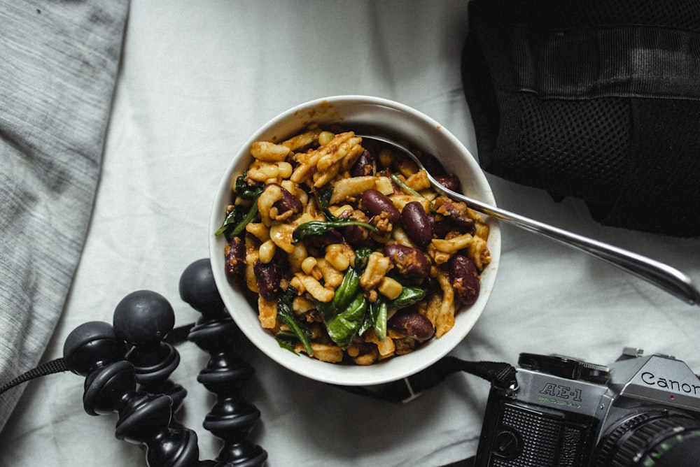 a white bowl filled with pasta next to a camera