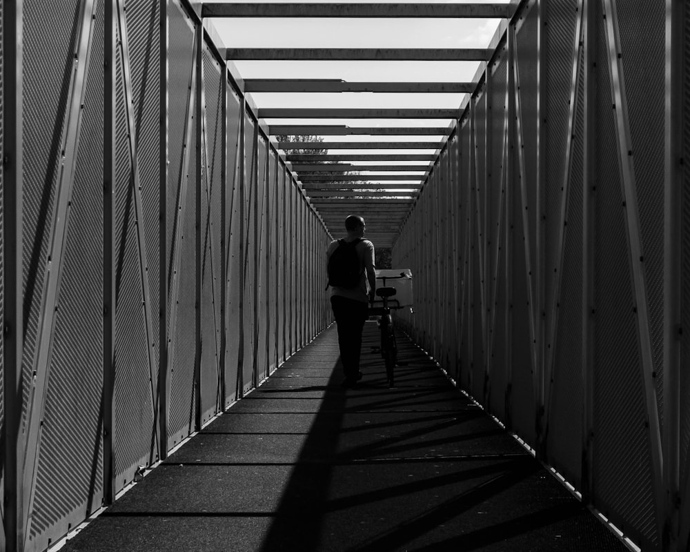 grayscale photo of man walking on the hallway