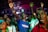 A group of people appears to be deeply engaged in an emotional experience, possibly during a concert or religious gathering. Many have their eyes closed and hands raised, suggesting a sense of euphoria or spiritual connection. The lighting is dynamic, casting colorful hues across the crowd.