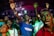 A group of people appears to be deeply engaged in an emotional experience, possibly during a concert or religious gathering. Many have their eyes closed and hands raised, suggesting a sense of euphoria or spiritual connection. The lighting is dynamic, casting colorful hues across the crowd.