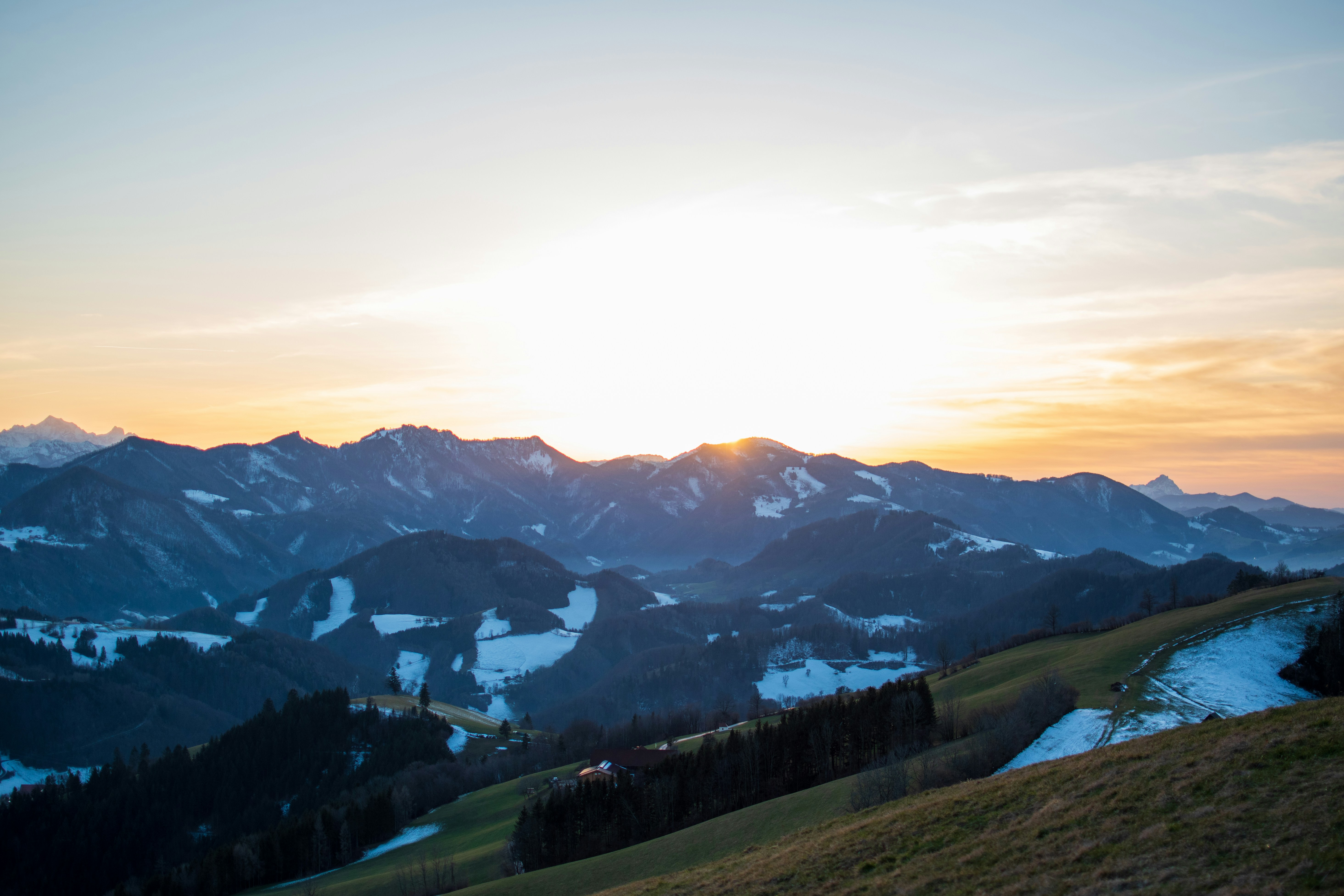 grüne Bäume und Berge unter weißen Wolken und blauem Himmel tagsüber