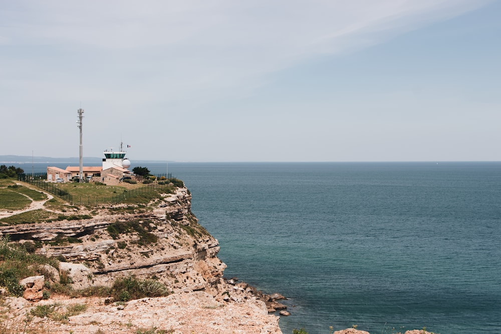 white and brown house on cliff by the sea under white sky during daytime