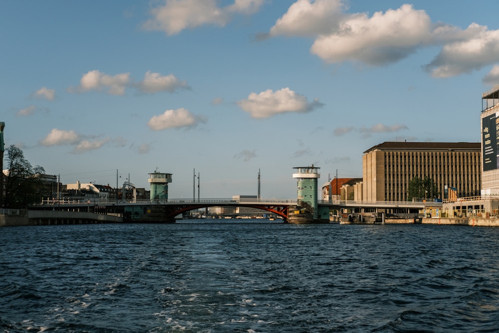 Bateau blanc et brun sur l’eau près du pont sous le ciel bleu pendant la journée