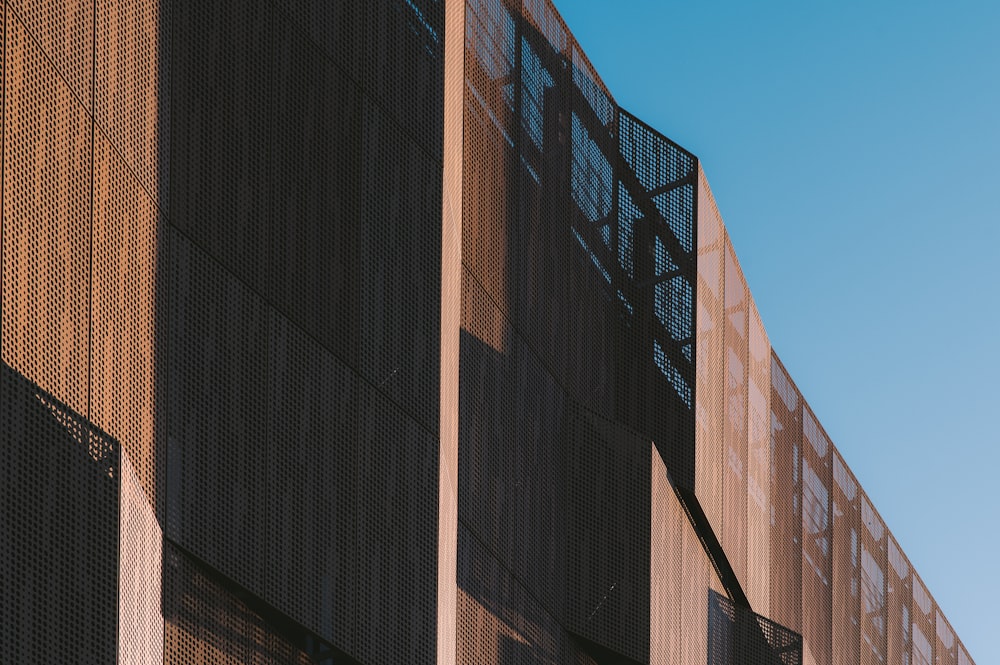 edifício de concreto marrom e preto sob o céu azul durante o dia