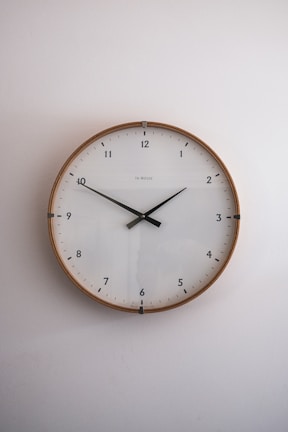 A classic round wall clock featuring a wooden finish and elegant hands.