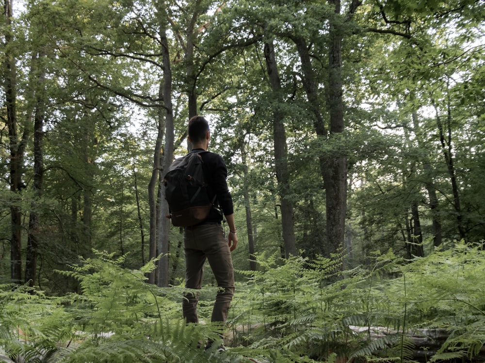 man in black jacket and black pants walking on forest during daytime