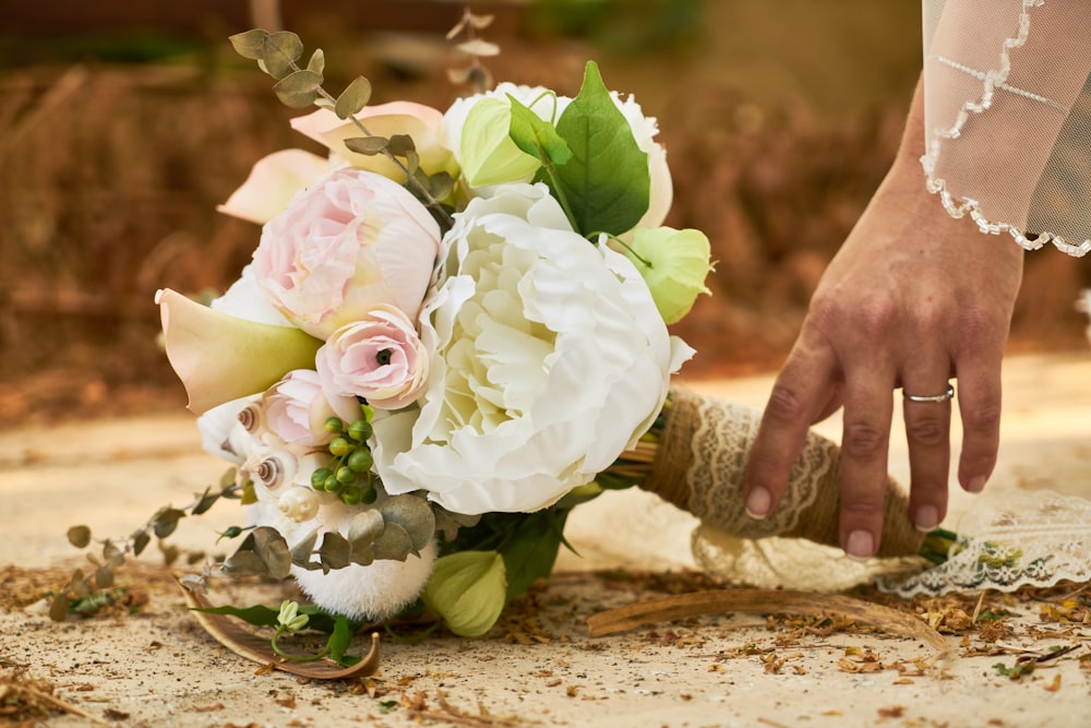 person holding white and pink rose bouquet