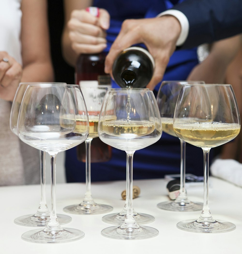 person pouring wine on wine glass