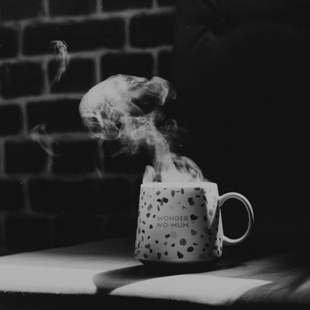 grayscale photo of white ceramic mug on table