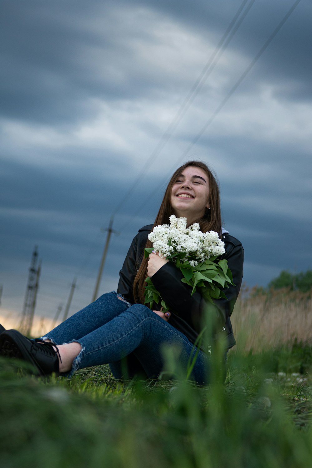 woman in blue denim jeans holding white flowers