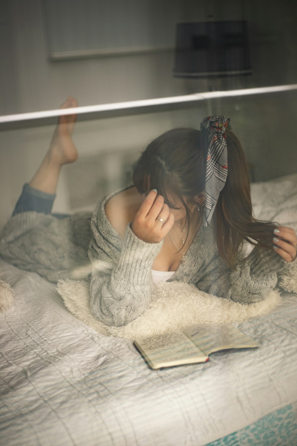 woman in white knit sweater reading book