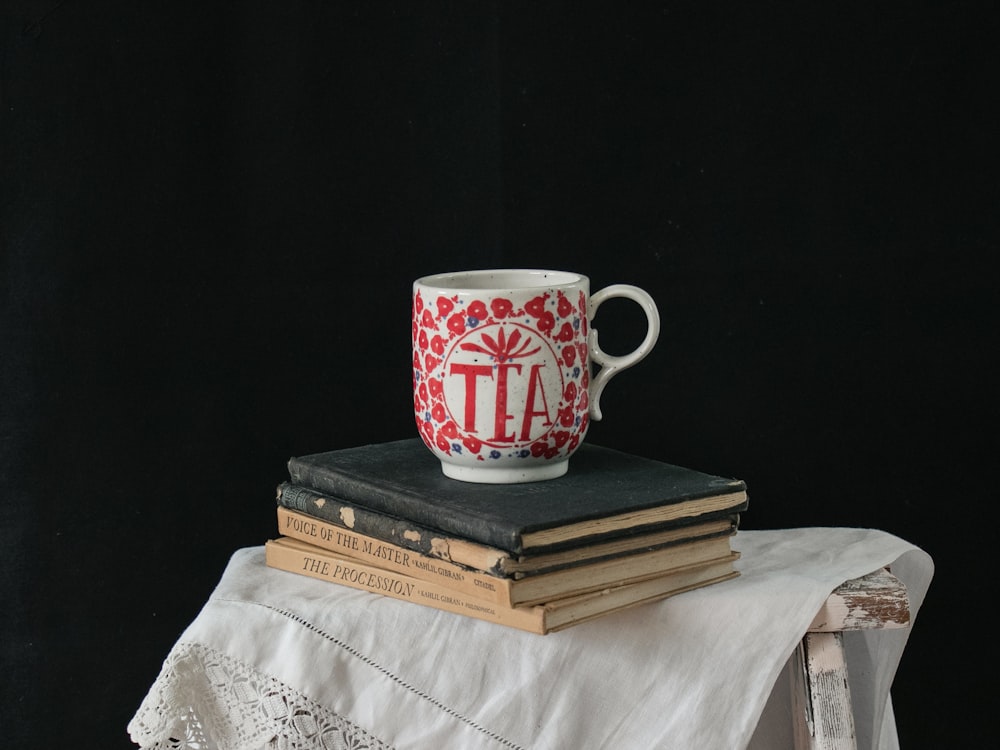 white and red ceramic mug on brown book