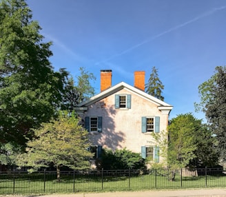 white and brown house near green trees under blue sky during daytime