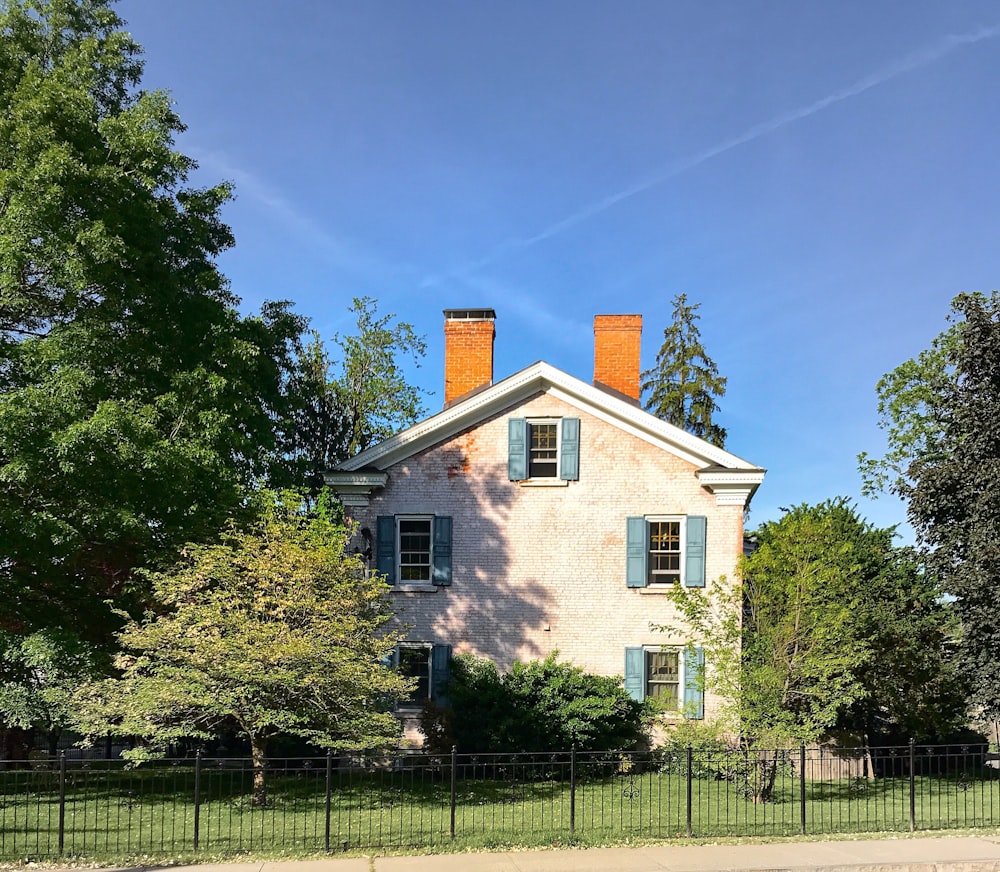 white and brown house near green trees under blue sky during daytime