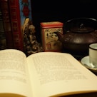 A collection of open books and a cup of tea on a cozy table.