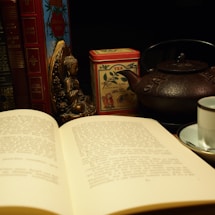 A serene workspace with traditional Eastern metaphysics books and a cup of tea on a wooden table.