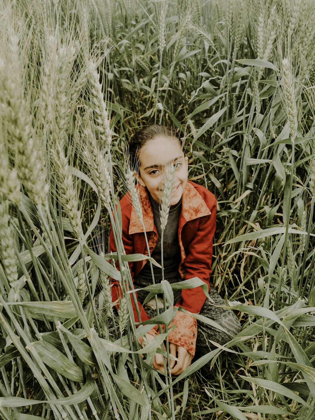 woman in red coat standing on green grass field during daytime