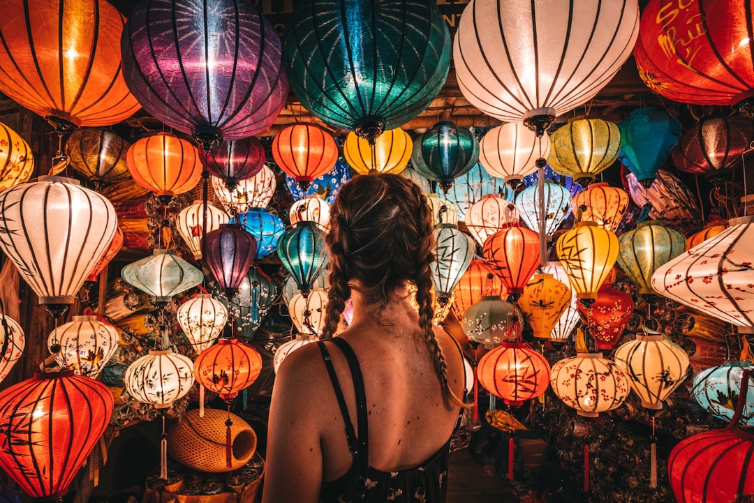 woman in black tank top standing near blue and red paper lanterns