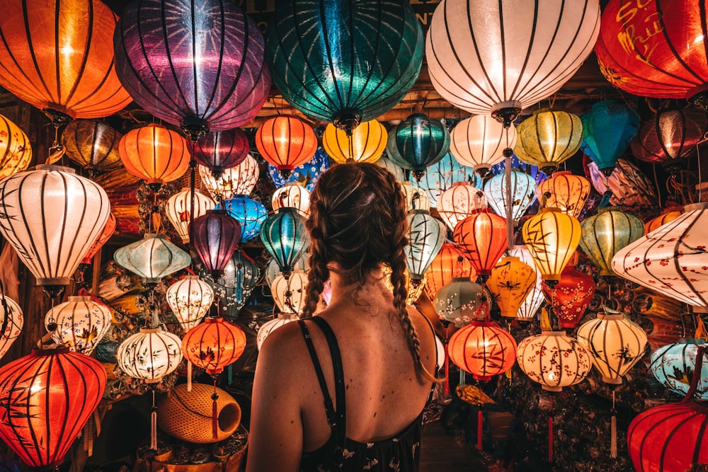 woman in black tank top standing near blue and red paper lanterns