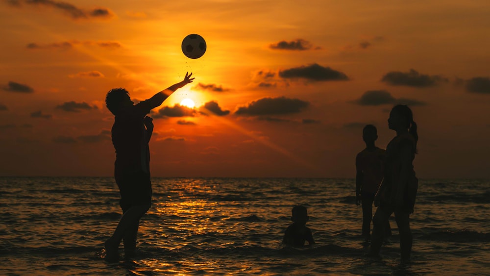 silhouette of 2 people standing on beach during sunset