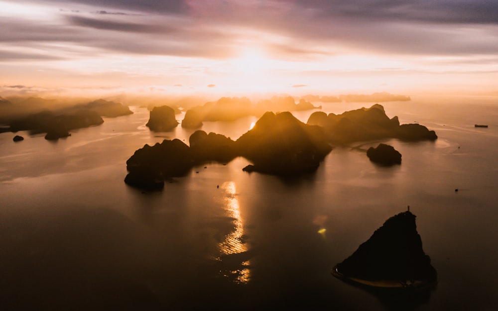 silhouette of rocks on water during sunset