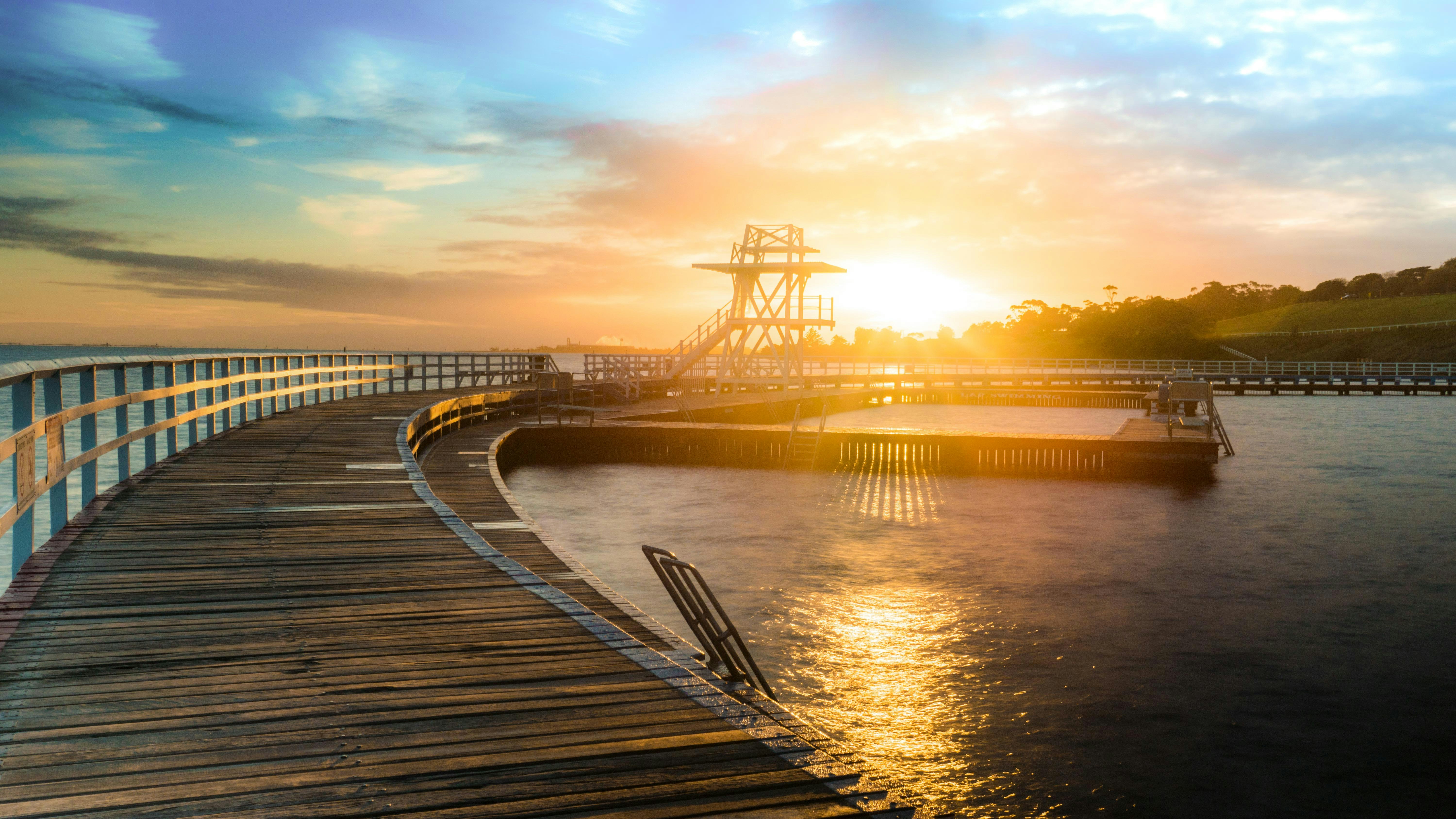 일몰 동안 수역에 갈색 나무 선착장