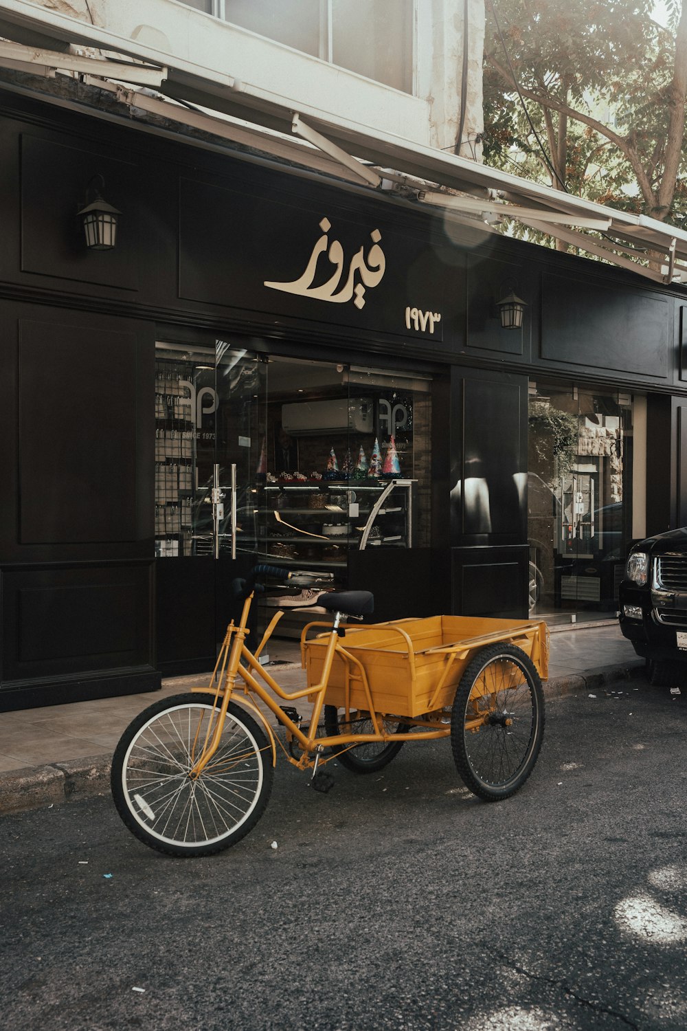 Triciclo negro y marrón estacionado junto a una tienda de madera marrón durante el día