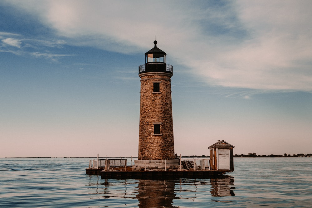 brown and white concrete lighthouse near body of water during daytime