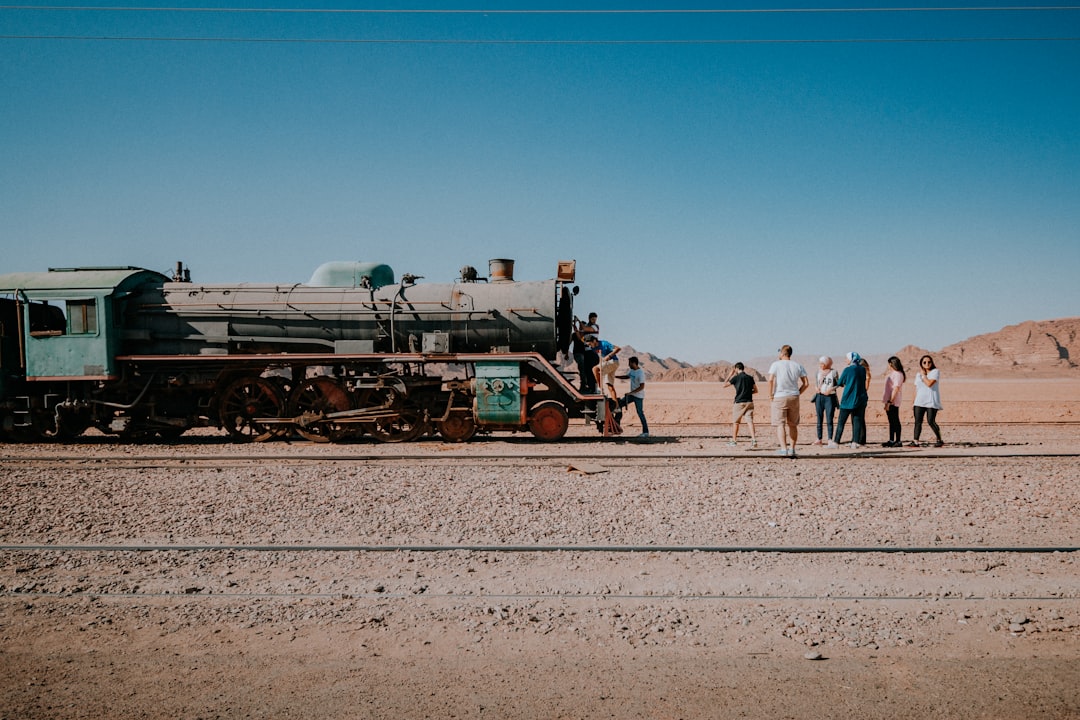 people standing near green and black train under blue sky during daytime