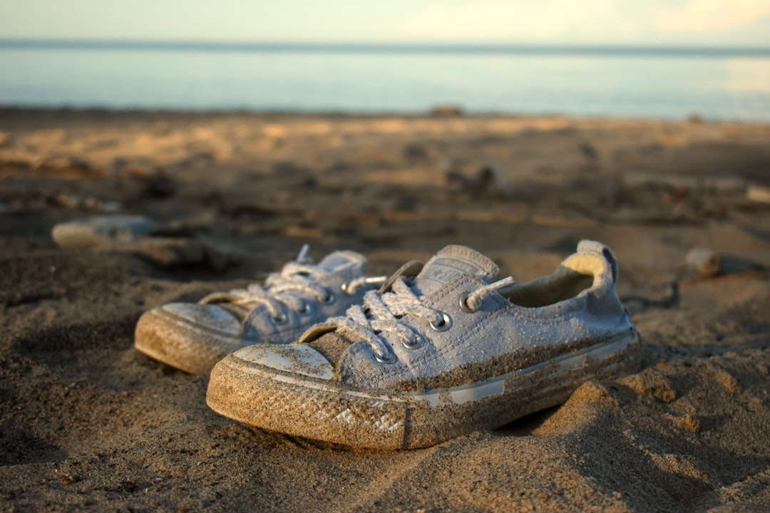 gray and white low top sneakers on brown sand during daytime