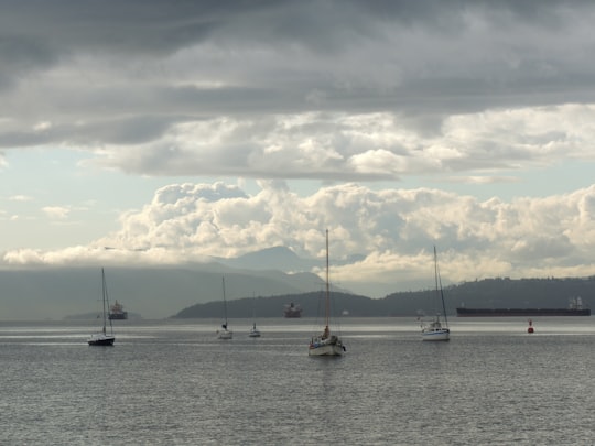 white and yellow boat on sea under white clouds during daytime in English Bay Canada