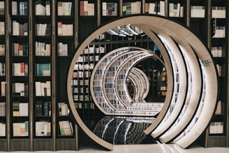 A library with bookshelves filled with various books forms a tunnel-like perspective with circular, mirrored arches. The arches create an illusion of infinity, with the polished floor reflecting the intricate architectural design.
