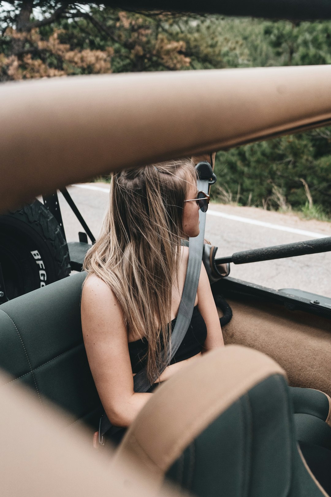 woman in black tank top driving car during daytime