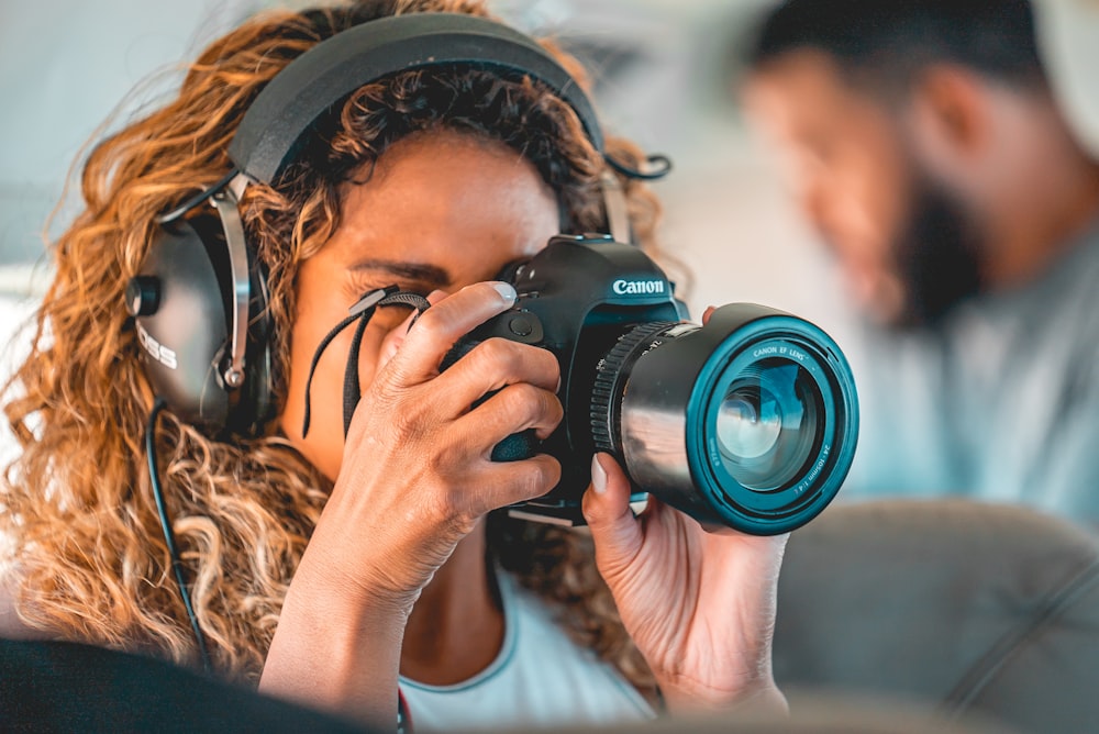 woman in white shirt holding black nikon dslr camera