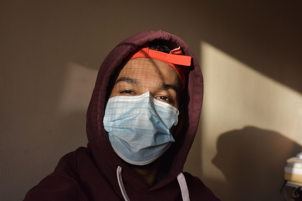 person in white face mask and red hoodie