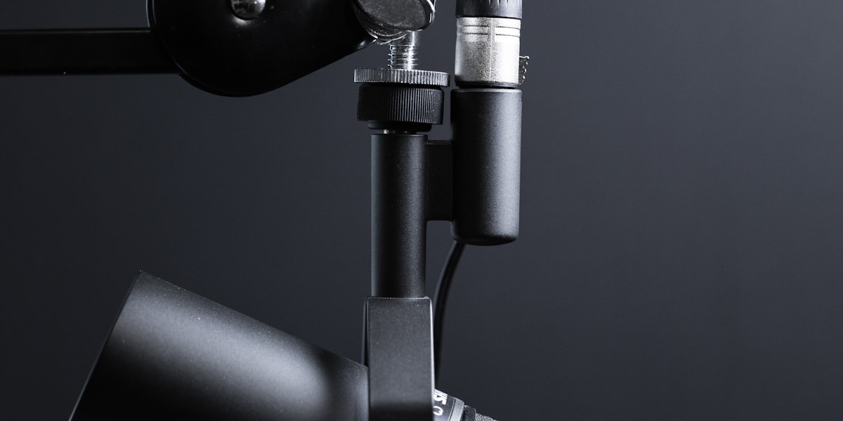 Nagrywanie podcastu – źródło: Unsplash Mikrofon podcastowy na statywie w studio nagraniowym