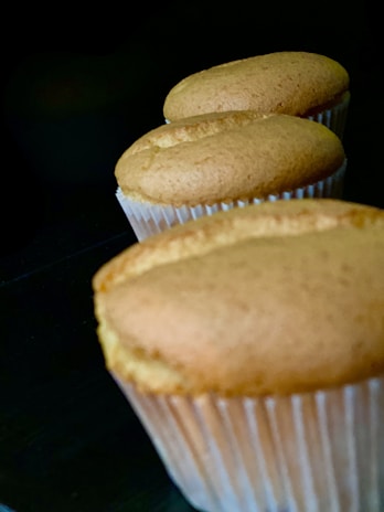 Rows of golden muffins rising in the oven with warm light