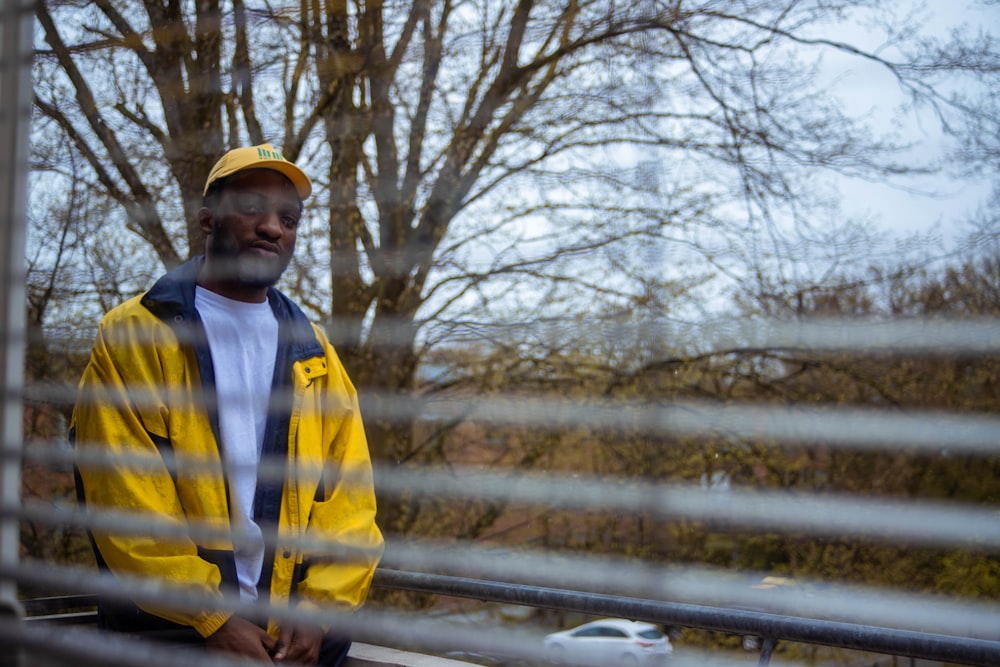 man in yellow and blue jacket standing near brown trees during daytime