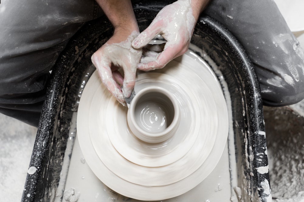person holding round white clay pot