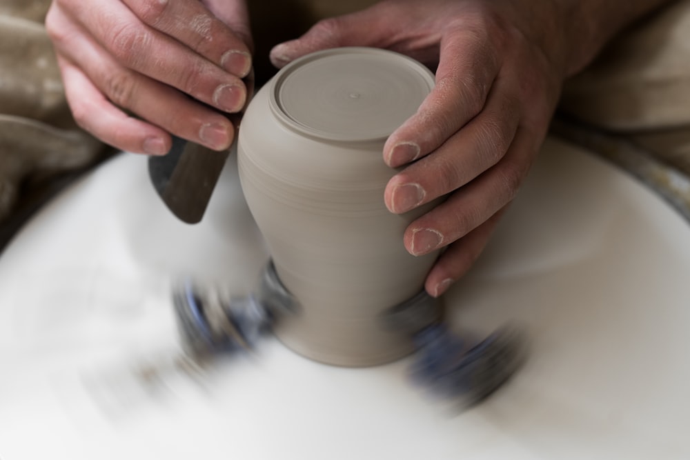 persona vertiendo líquido blanco en taza de cerámica blanca