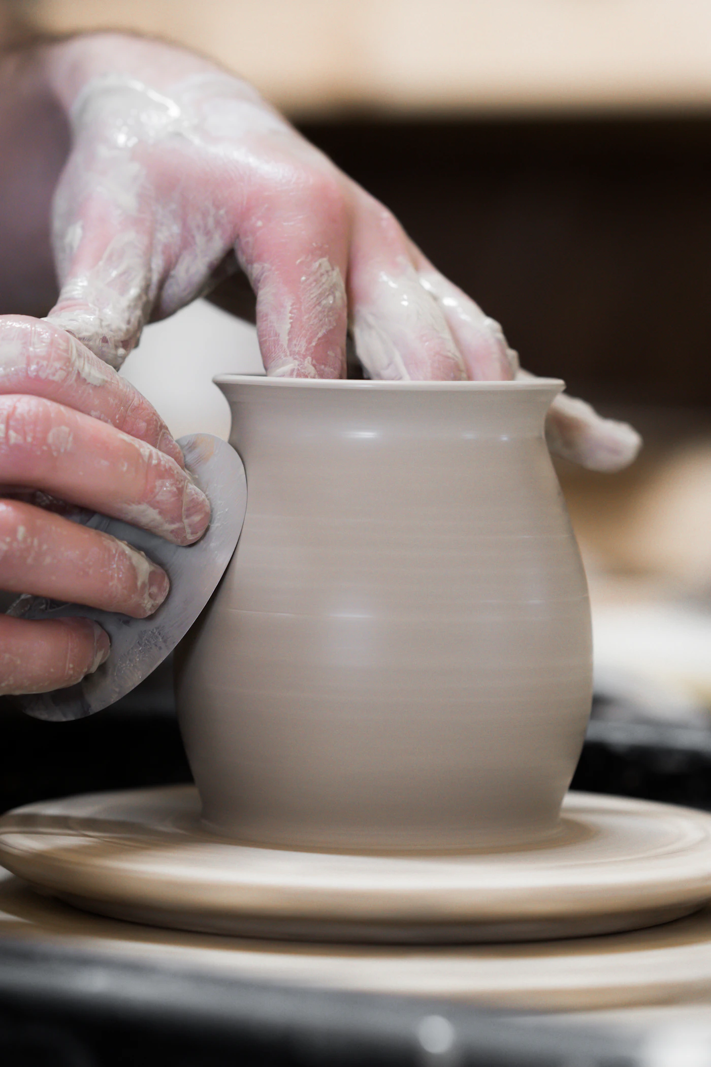 Handen schuren een pas gedraaide kom in het keramiek atelier