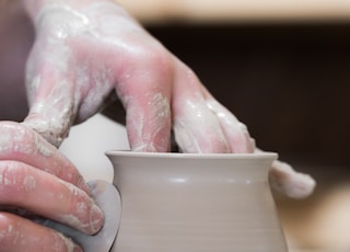 person holding white clay pot