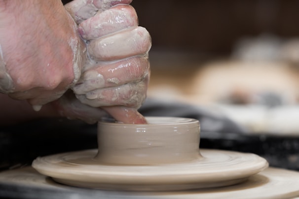 Close-up of hands molding clay on a pottery wheel, capturing the texture and focus.