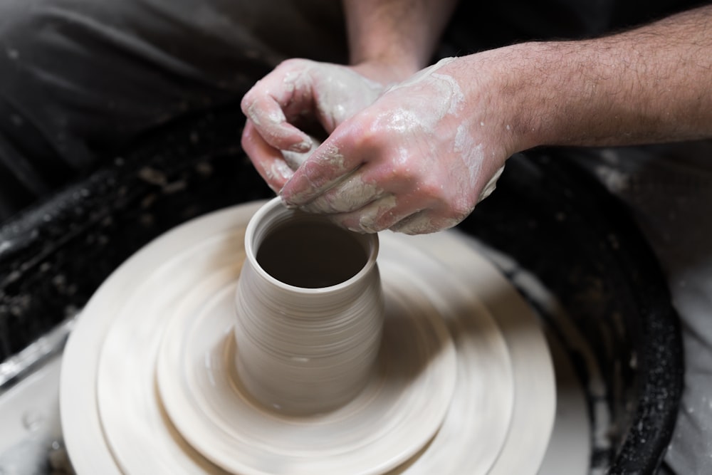 Persona che tiene il piatto rotondo in ceramica bianca