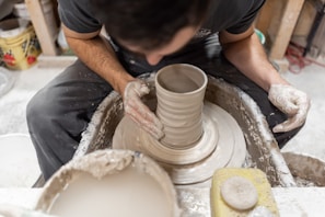 person making clay pot with brown powder