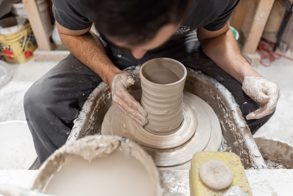 person making clay pot with brown powder