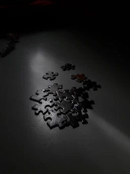 Dynamic anime character analyzing mysterious puzzle pieces in a dimly lit room.