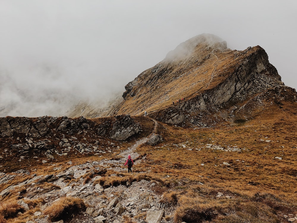 person walking on brown rocky mountain during daytime